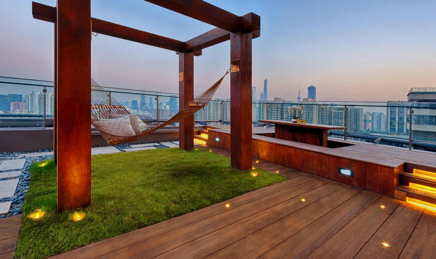 Gazon synthétique sur rooftop avec hamac et vue sur la ville au coucher du soleil
