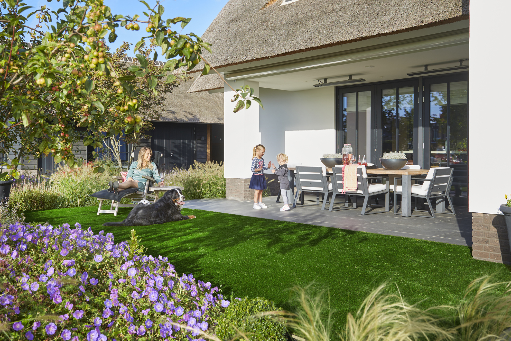 Famille et chien profitant d’un jardin d’été avec gazon synthétique