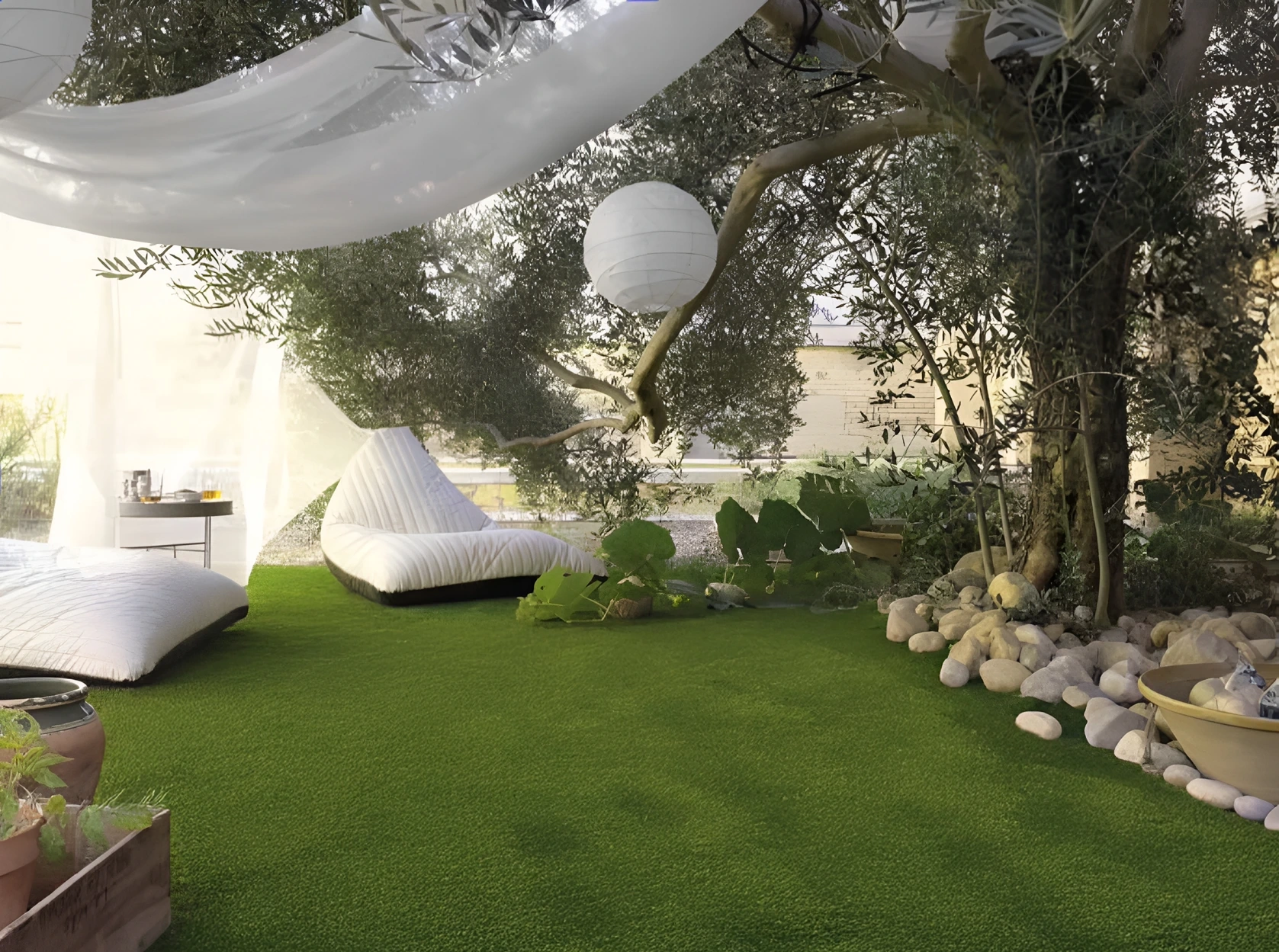 Petit salon de jardin installé sous un arbre sur un gazon synthétique verdoyant