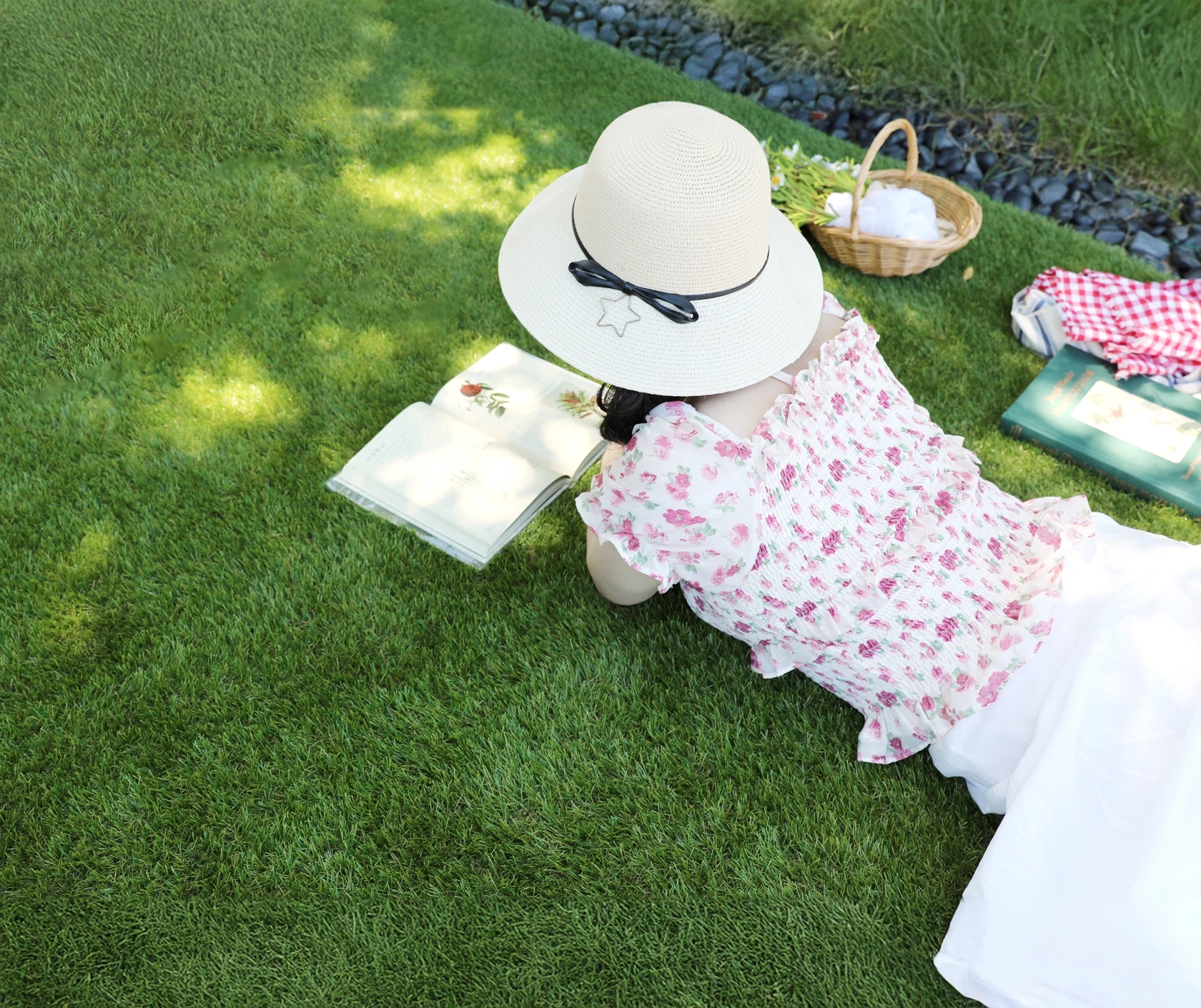 Femme allongée sur du gazon synthétique en train de lire au soleil