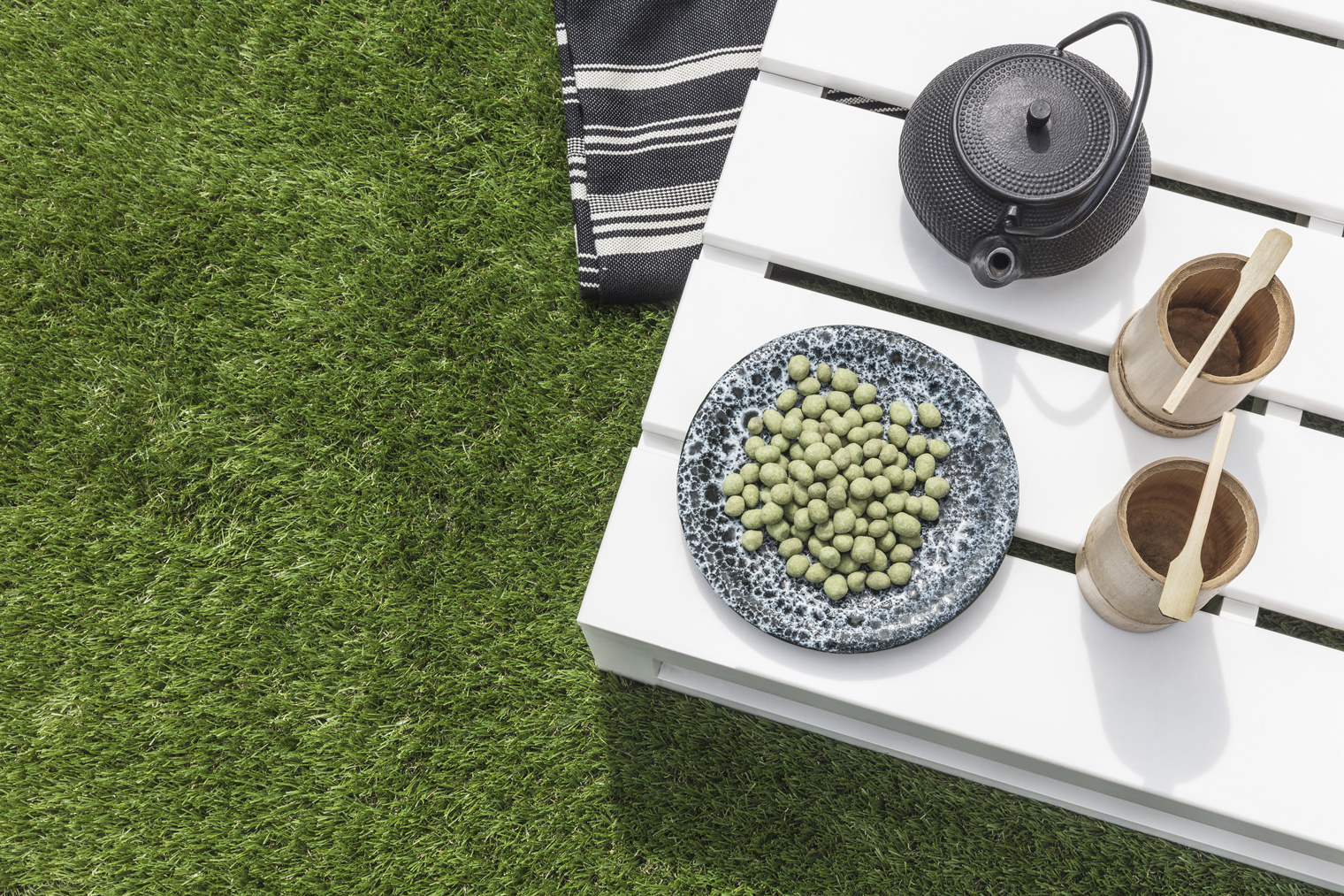 Table de salon de jardin avec tasse de thé posée sur du gazon synthétique