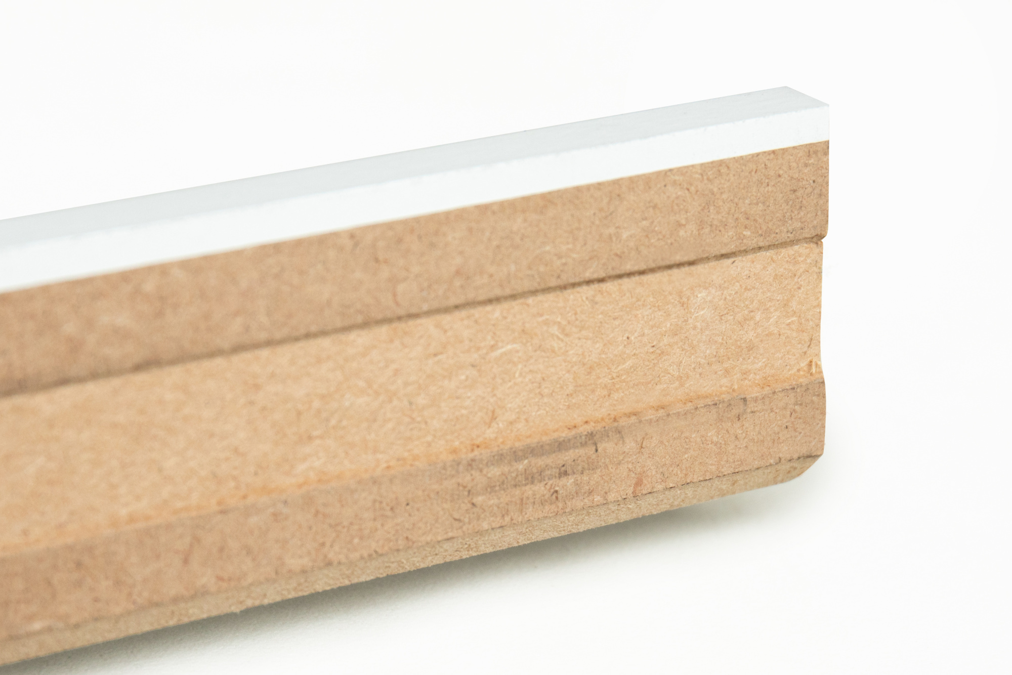 Vue détaillée du dos de la plinthe blanche à peindre et de sa rainure pour câbles