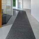 Tapis d'entrée côtelé antisalissures & antidérapant - Gris dans un couloir professionnel lumineux