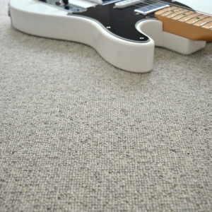 Moquette Killoo Gris en laine vierge avec détail de texture bouclée et instrument posé