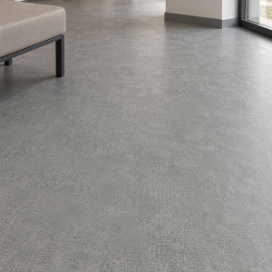 Sol PVC classé U3P3 - IPERFORM 370 - Pinnacles T83, aspect béton gris dans une pièce lumineuse avec canapé beige et grandes fenêtres