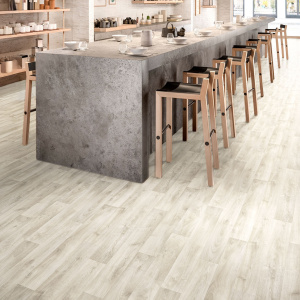 Sol vinyle Batimax Tavel T19 imitation parquet bois blanchi dans un restaurant lumineux avec comptoir en béton et tabourets hauts