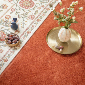 Moquette ultra douce Pulse cuivre brûlé, sol textile chaleureux avec tapis décoratif et fauteuil