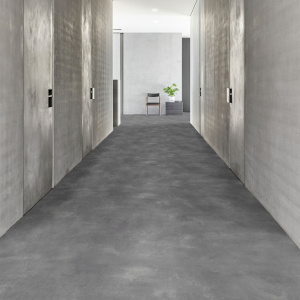 Sol vinyle Batimax Styx T98 aspect béton gris foncé dans un long couloir contemporain aux murs gris et portes latérales