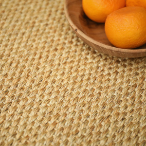 Zoom sur la texture du sisal Tulum coloris miel avec assiette en bois et fruits oranges