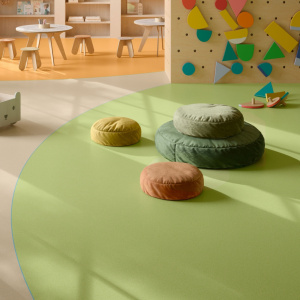 Sol vinyle Batimax Crystal T28 vert anis dans un espace de jeux pour enfants, avec coussins ronds et mur d'escalade coloré