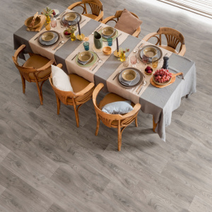 Sol vinyle Batimax Burned Wood T94 imitation parquet gris dans une salle à manger avec grande table dressée dans une salle à manger