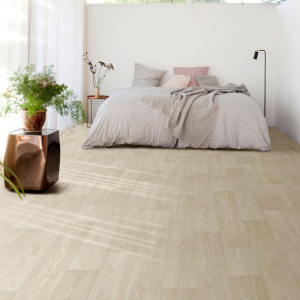 Sol vinyle Batimax Stockholm T37 imitation parquet chêne clair dans une chambre lumineuse avec lit bas, coussins et plantes vertes
