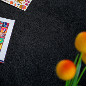 Tapis sur mesure Pulse noir graphite, texture velours avec magazines et fleurs colorées