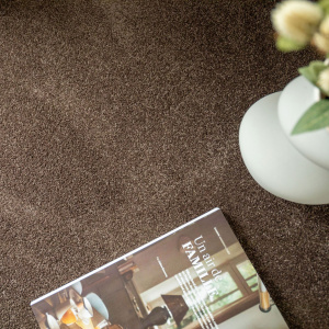 Moquette en polyester recyclé Re-cycle Chocolat, sol doux et confortable avec magazine posé sur la surface