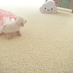 Moquette laine vierge Latoon Écru dans une chambre d’enfant avec peluche et coussin nuage