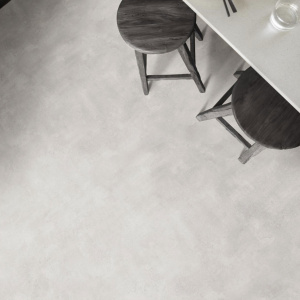Sol vinyle Prestige Batitec - Styx T07 aspect béton clair dans un espace repas contemporain avec table blanche et chaises foncées