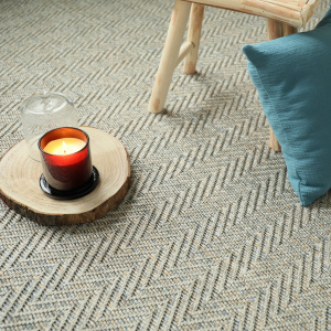 Moquette Java Chevron Gris grège avec bougie et coussin dans une ambiance cosy et élégante