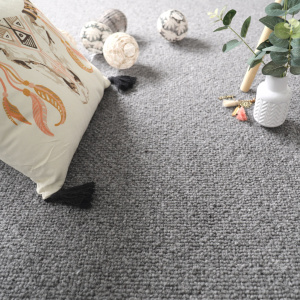 Moquette laine vierge Latoon Gris foncé avec coussins et vase dans une ambiance douce et moderne