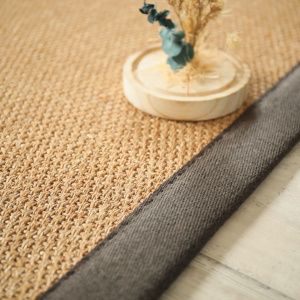 Finition ganse chocolat du tapis en sisal Tulum havane, mise en scène avec éléments naturels