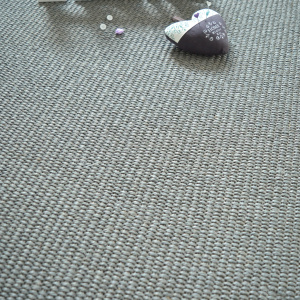 Sisal Quintana Gris en détail avec objet textile et petits éléments décoratifs sur tissage bouclé