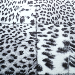 Gros plan sur les carrés patchwork du tapis toucher soft léopard noir et blanc, coutures visibles entre les motifs