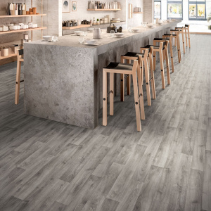 Sol vinyle Batimax Tavel T17 imitation parquet bois gris dans un restaurant lumineux avec comptoir en béton et tabourets hauts