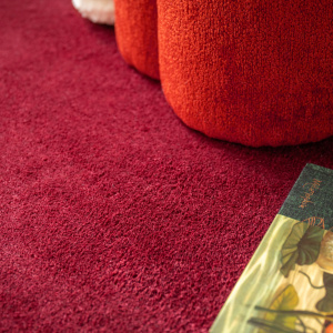Moquette ultra douce Pulse rouge grenat, texture velours dense avec pouf et livre