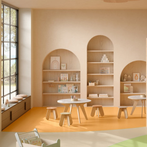 Sol vinyle Batimax Crystal T16 orange dans un espace ludique lumineux, avec tables en bois clair, chaises et étagères en alcôves