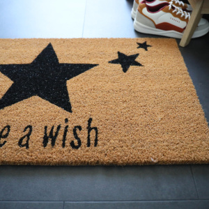 Paillasson Coco 45 x 75 cm - Étoiles posé devant des chaussures, paillasson en fibres naturelles de coco dans une entrée intérieure