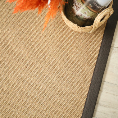 Vue du tapis en sisal Tulum havane bordé d’une ganse chocolat, décoration végétale et panier