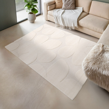 Tapis Flower Power crème en relief sous un canapé beige, pour une déco cocooning et élégante