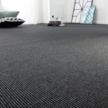 Moquette tissé plat Nusa gris ardoise posée dans un grand espace intérieur lumineux