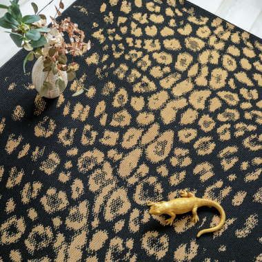 Tapis léopard noir et doré dans salon avec motif animalier et ambiance élégante