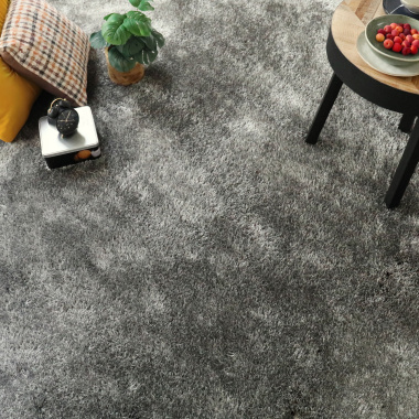 Tapis sur mesure velours épais Éclat FusionBac shaggy gris foncé 30 mm dans un salon cosy avec coussins et table basse