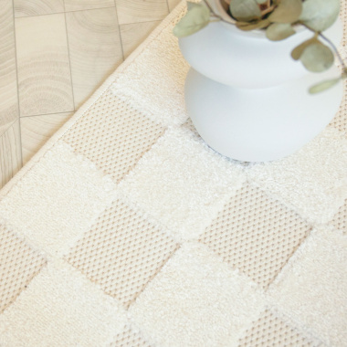 Carreaux en relief du tapis Petit Marius crème avec vase déco en teinte douce