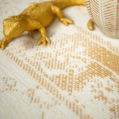 Zoom sur les motifs dorés du tapis pour chambre ou salon Soraya crème dans une ambiance déco