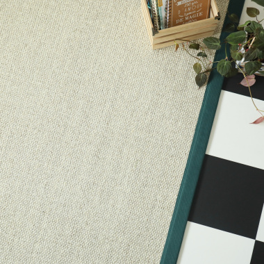 Tapis sur mesure en sisal Tulum blanchi, ganse vert émeraude, à côté de plantes dans une ambiance lumineuse et graphique