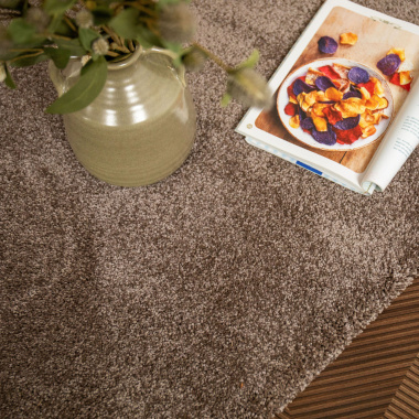 Tapis Select Chocolat, velours épais mis en scène avec vase et magazine