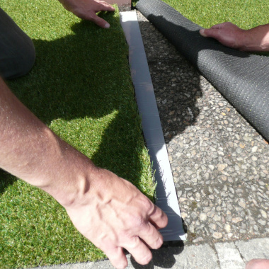 Repose du gazon synthétique sur la bande de jonction autocollante