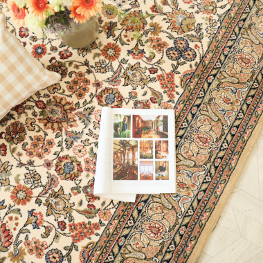 Tapis Mamie in love corail doux en détail avec coussin à carreaux et magazine ouvert