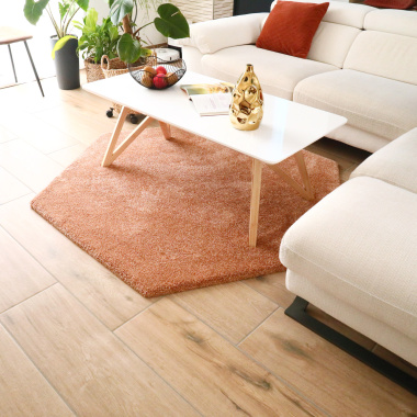 Tapis hexagonal Touch rose corail dans un salon lumineux avec canapé blanc