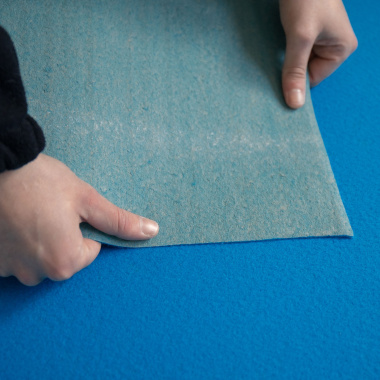 Détail de l'envers de la Moquette Stand Event Bleu azur manipulée pour montrer sa souplesse