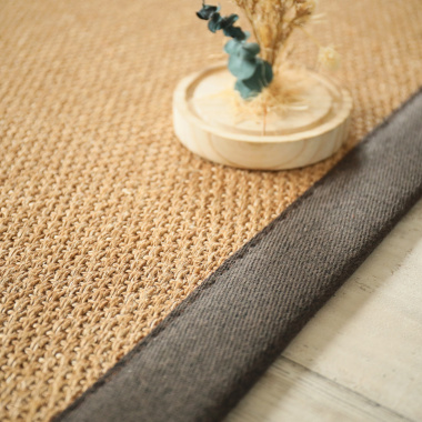 Finition ganse chocolat du tapis en sisal Tulum havane, mise en scène avec éléments naturels