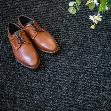 Tapis d’entrée côtelé anthracite, chaussures marron sur surface texturée