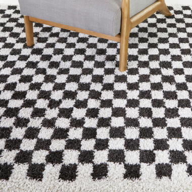 Tapis à damier Colorama noir et blanc à poils longs sous fauteuil en bois