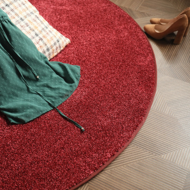 Tapis rond en velours rouge passion créant une atmosphère douce et enveloppante dans un espace salon
