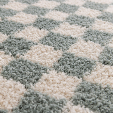 Zoom sur le tissage et la matière du tapis damier à poils longs Colorama vert d’eau