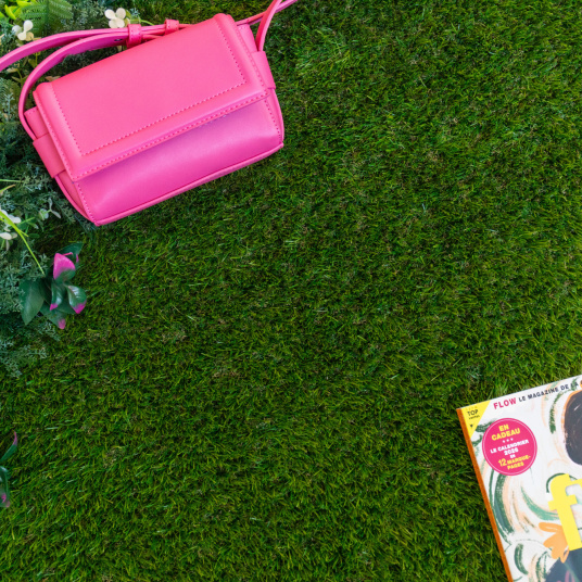 Gazon synthétique Nomade - 34 mm - À raccord scratch, pelouse verte vue de dessus avec sac rose et magazine coloré