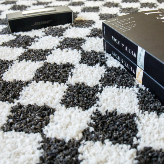 Tapis damier à poils longs Colorama - Noir et blanc associé à des livres pour une mise en scène graphique
