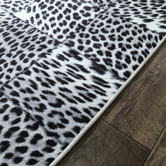 Détail de la bordure du tapis toucher soft léopard noir et blanc, finition fine et régulière posée sur parquet bois